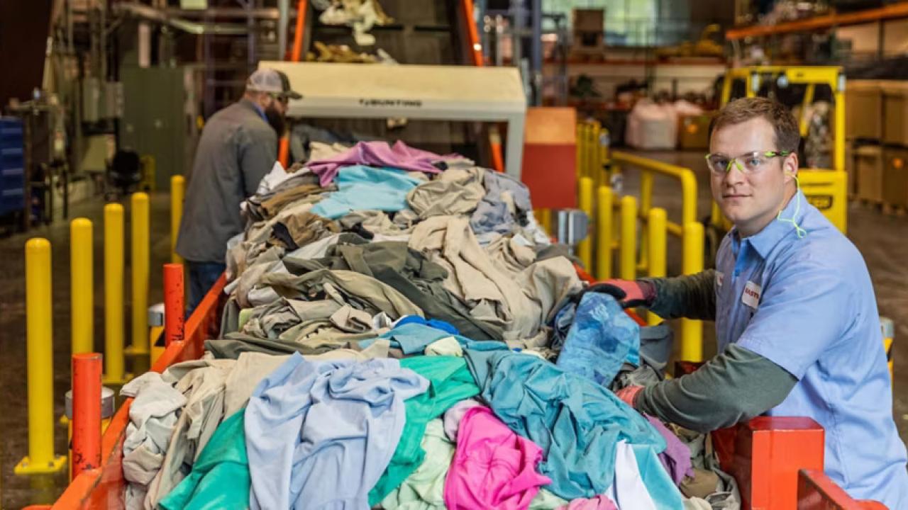 A person next to a line of waste textiles.