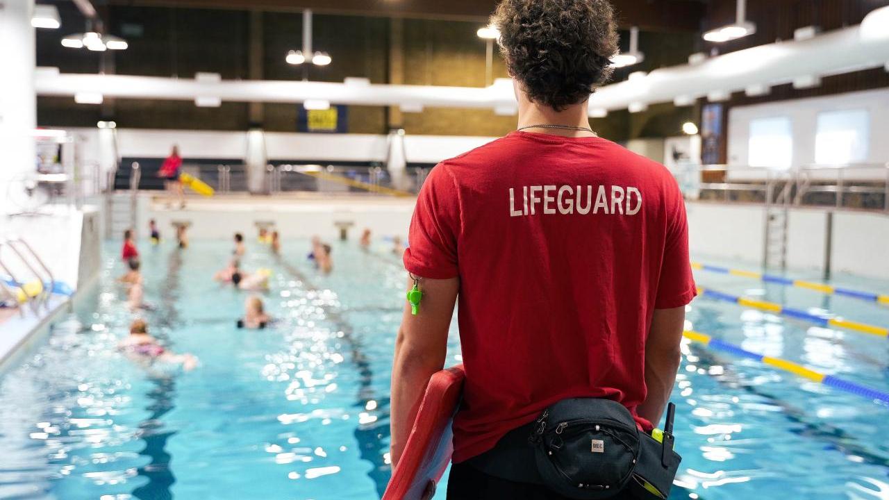 A life guard looking out over a large indoor pool with swimmers.