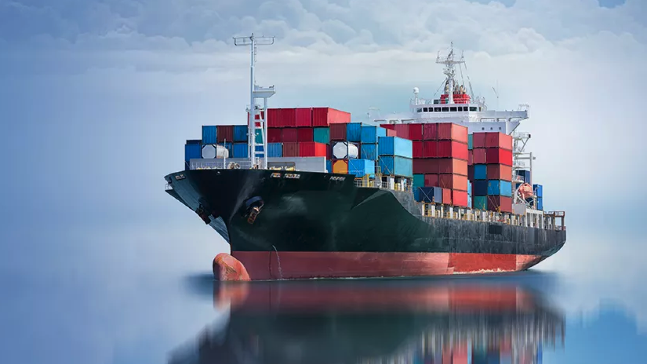 A cargo ship on still water with a cloudy blue sky