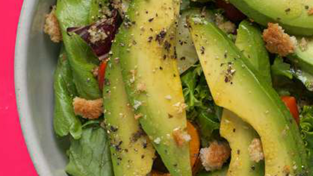 Close up of a bowl of sliced Avocado and other vegetables and seasonings