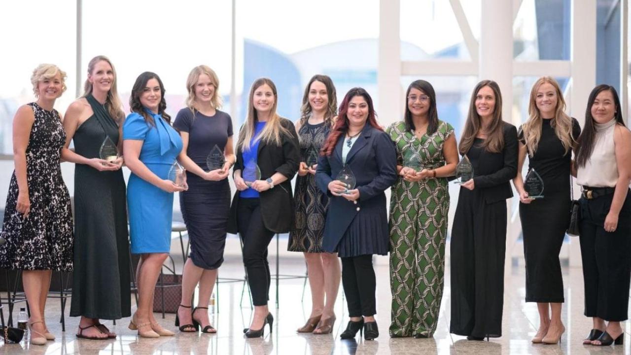 A group of people in a row, each holding an award.