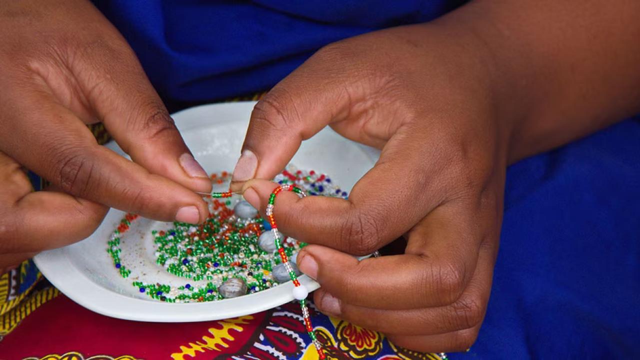 Close up of a person stringing beads.