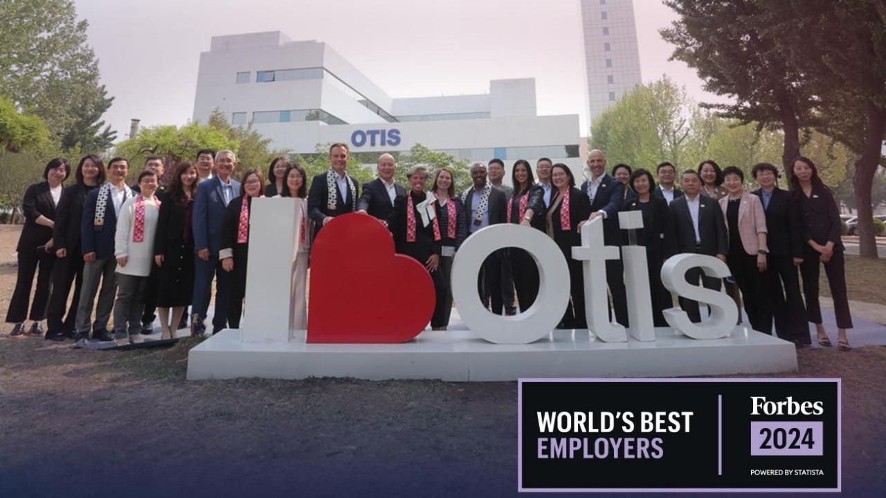 A large group posed outtside, behind a "I 'heart' Otis" sign. Forbes 2024 World's Best Employers logo in the corner.