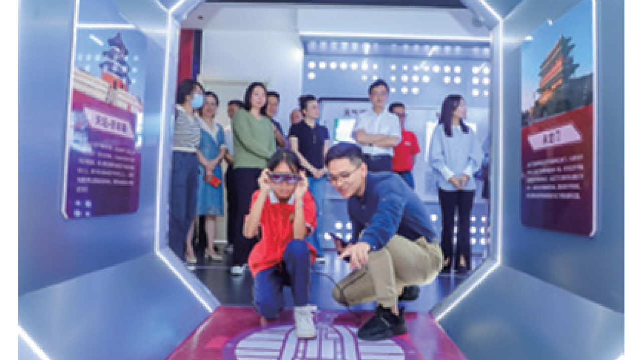 An adult and child crouched in an octagonal room with displays on each side. Others standing and waiting behind them.