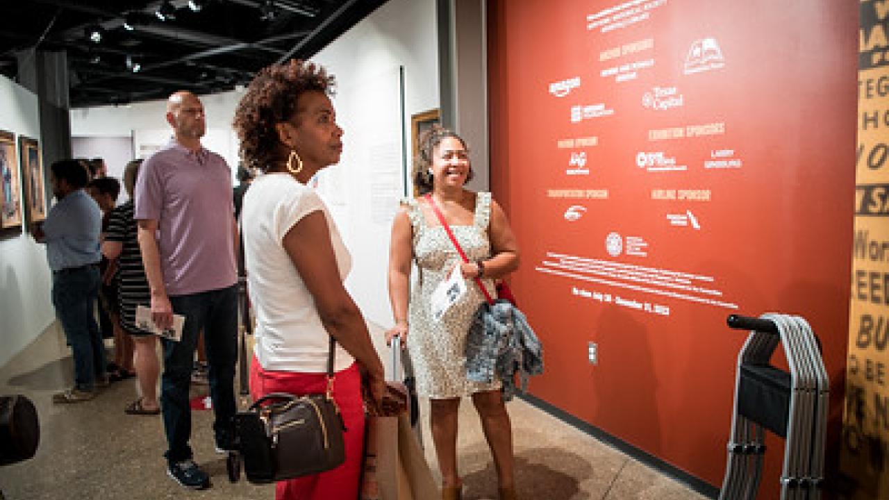 People attending a museum opening, viewing exhibits.