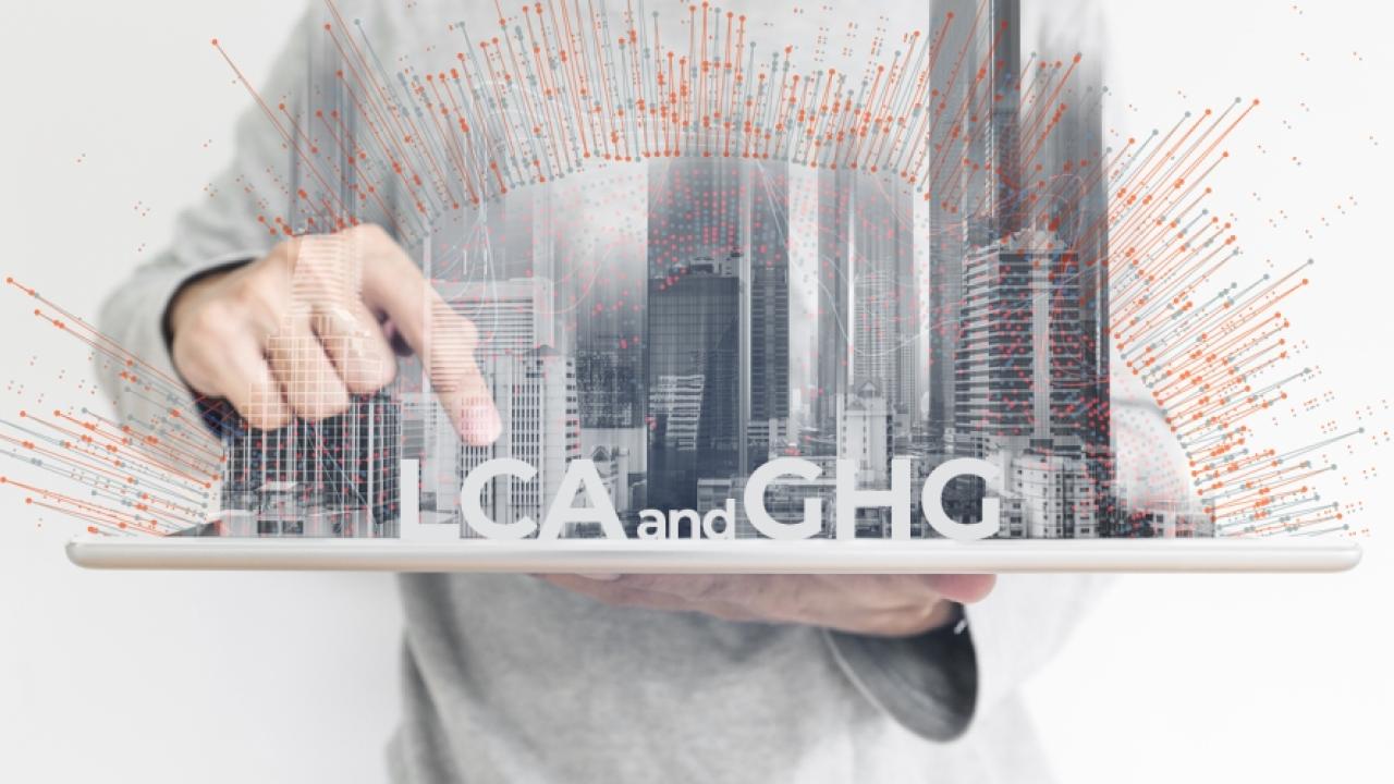 abstract of person holding a city on a board pointing to words "lca or ghg"