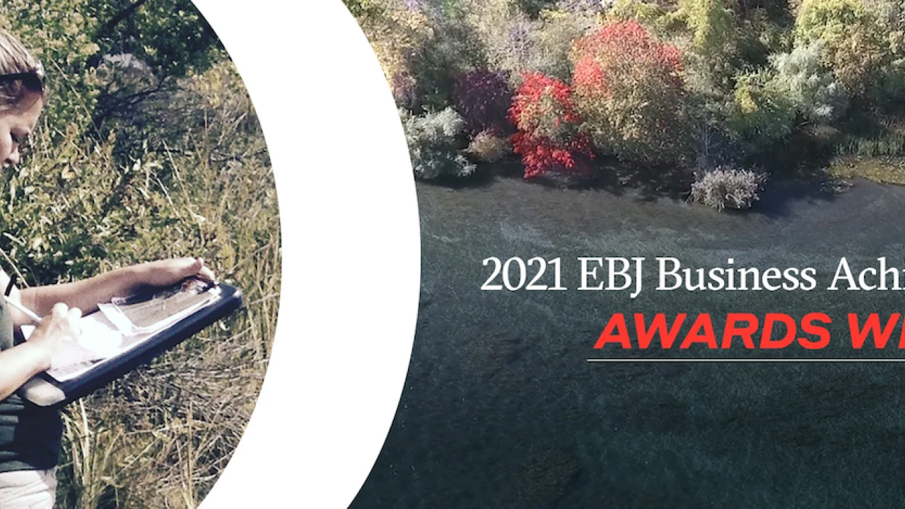 Person writing on clipboard with text that reads: 2021 EBJ Business Achievement Awards Winner