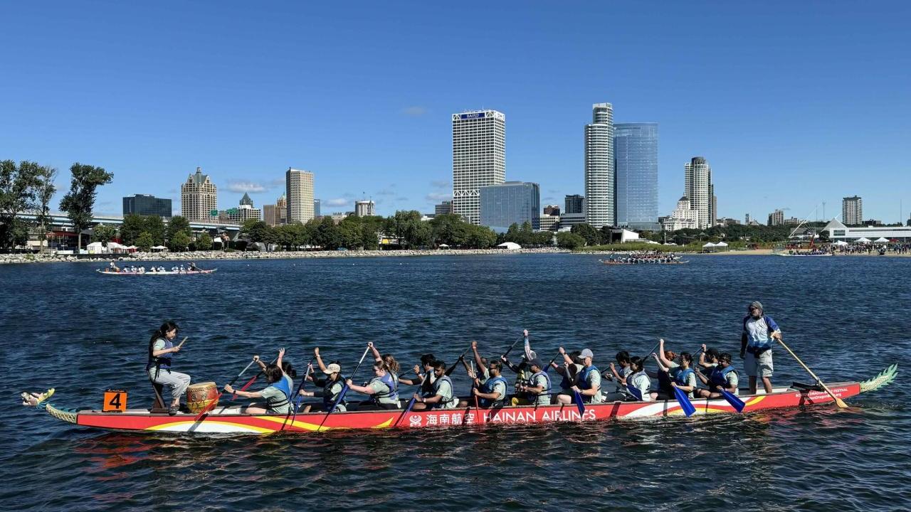 A group in a long boat paddling on a body of water.