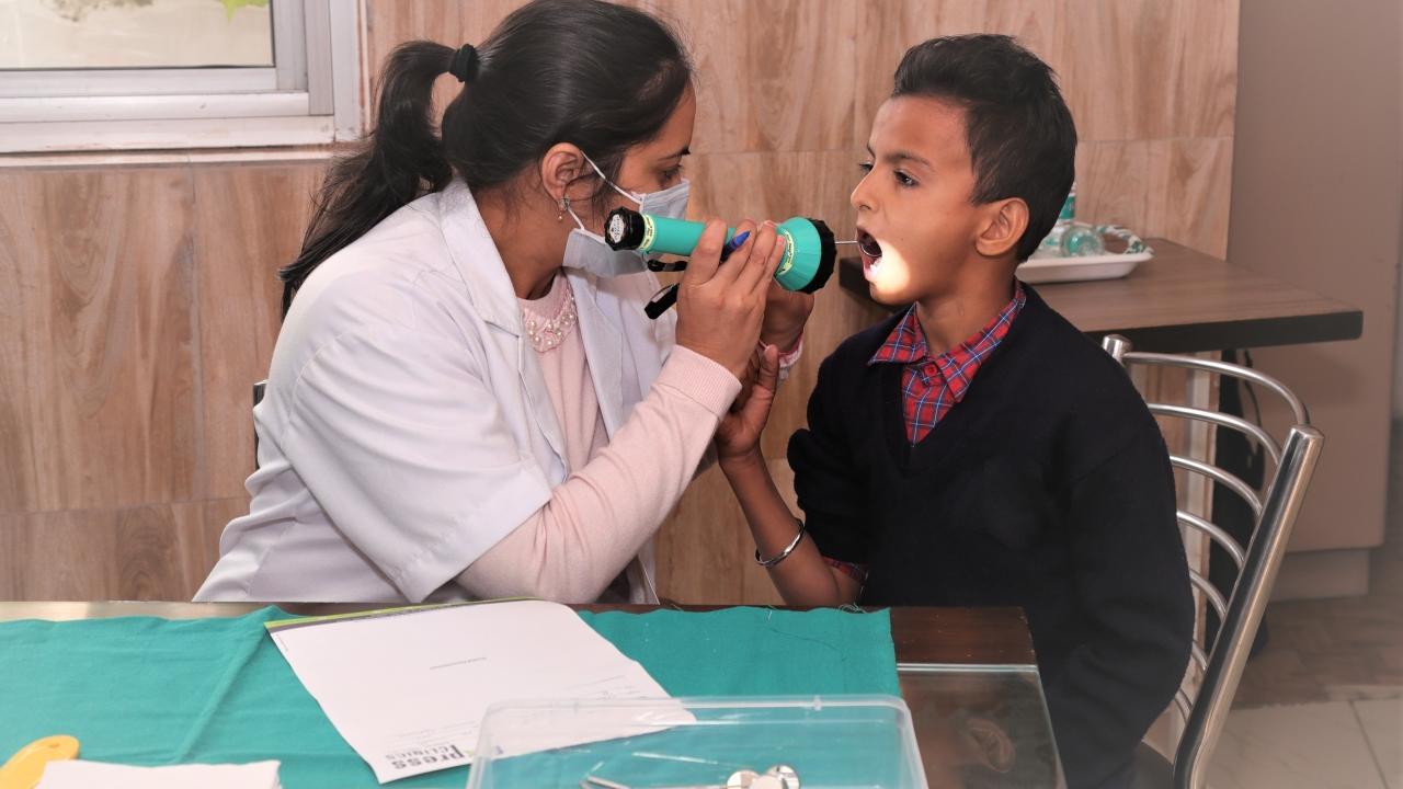 Person looking in a childs' mouth with a flashlight