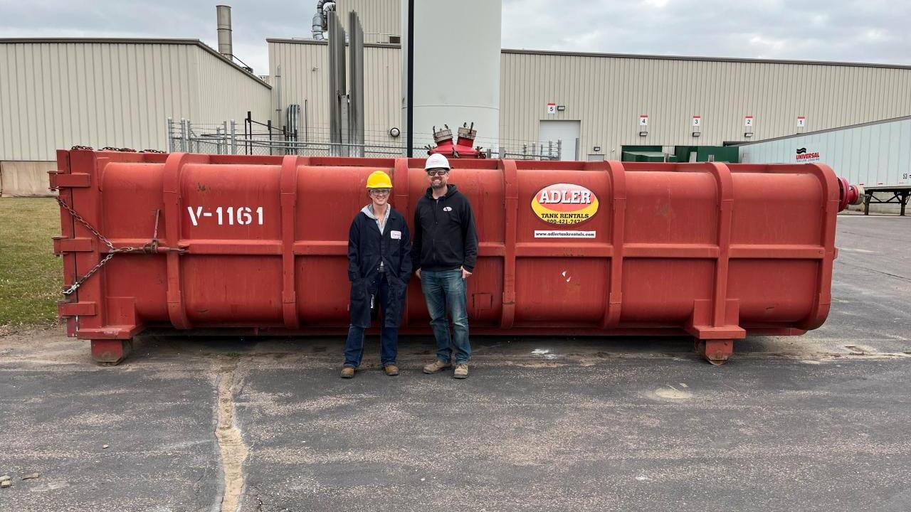 Two people in front of a tank