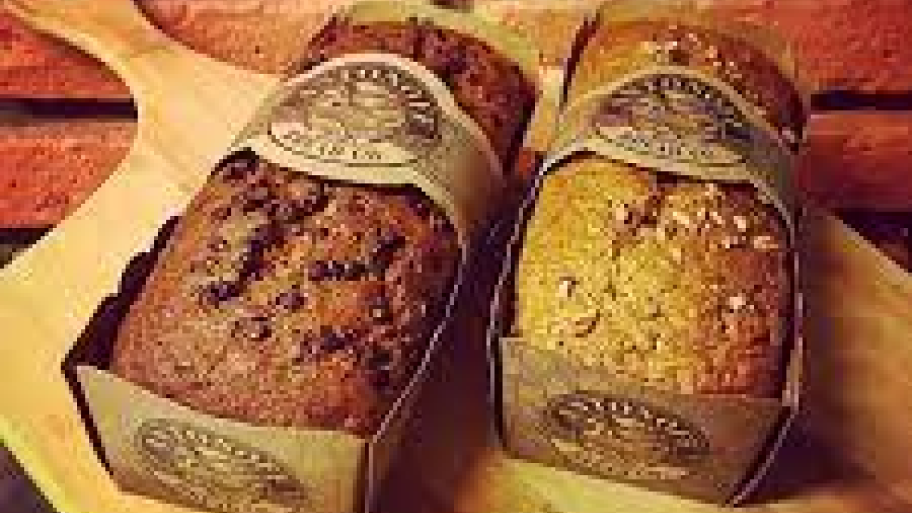 two loaves of packaged bread on a wooden board in front of a brick wall