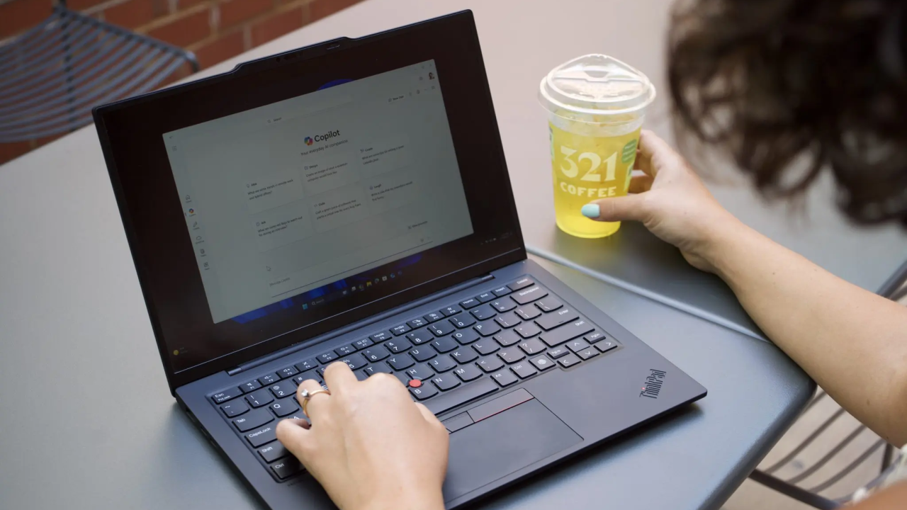 Someone using a laptop while holding a beverage
