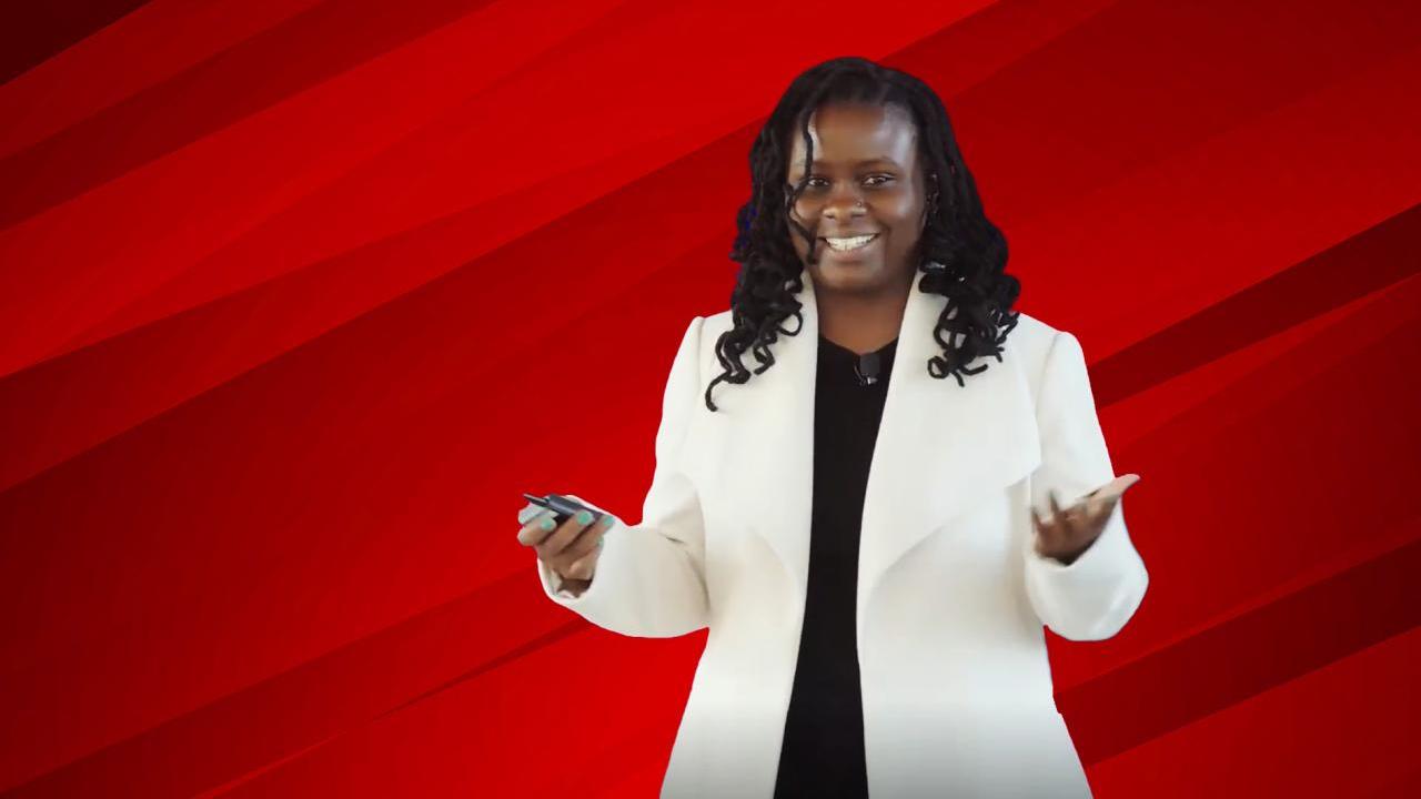 A person smiling with their hands out in front of a red background