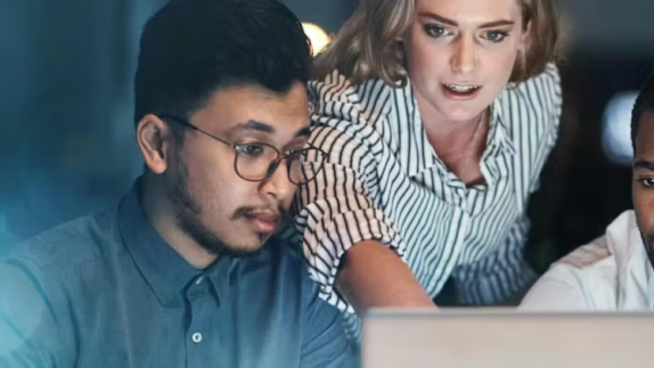 Three people looking at a laptop screen