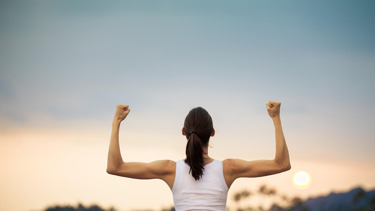 Person flexing muscles at sunrise