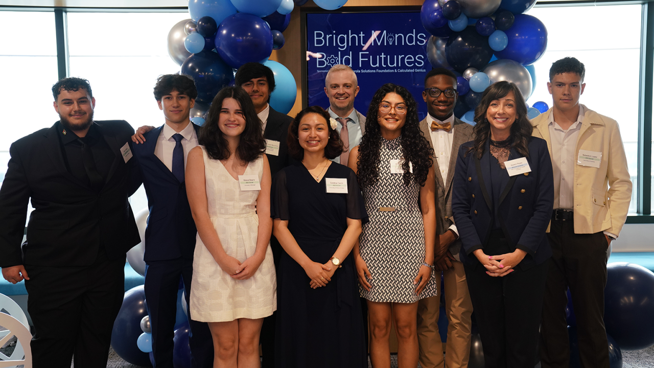 People smiling and standing together under blue balloons