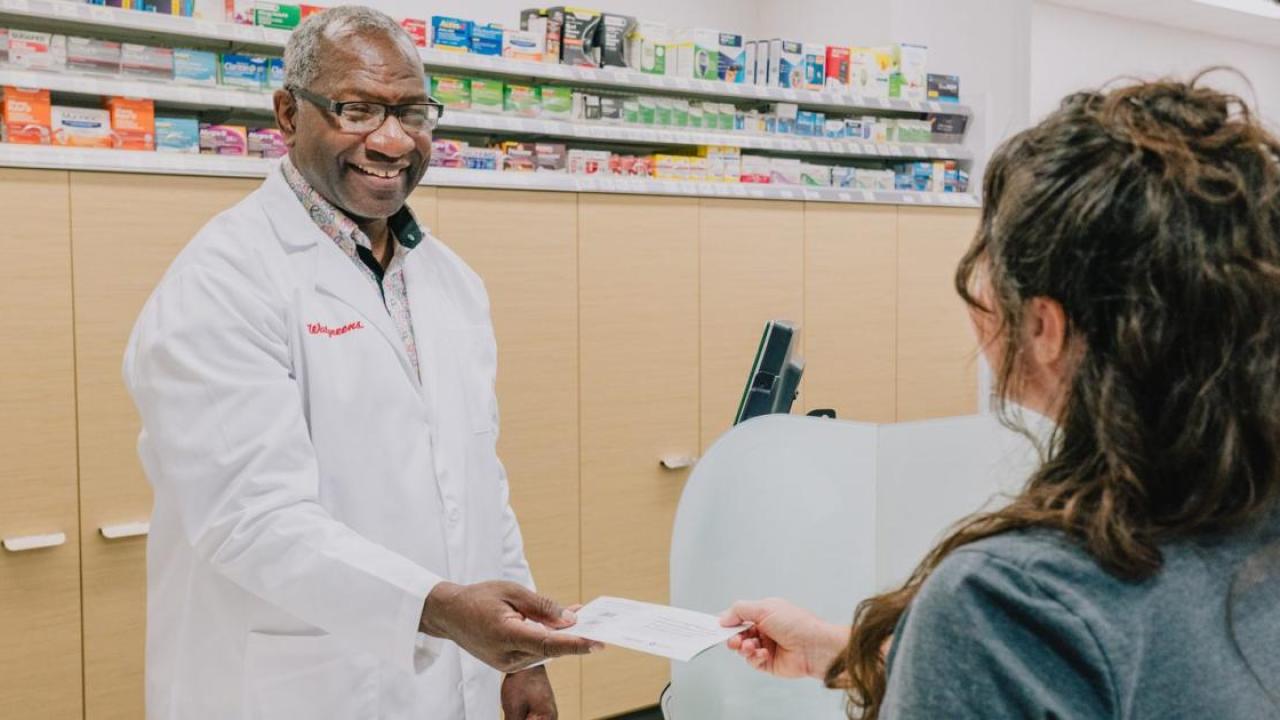 Calvin Bryant, pharmacist, handing something to a customer.