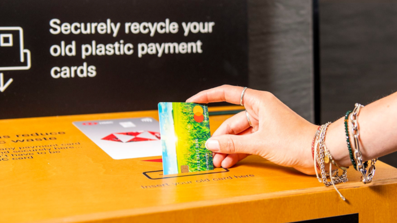 A person depositing a credit card into a recycling machine