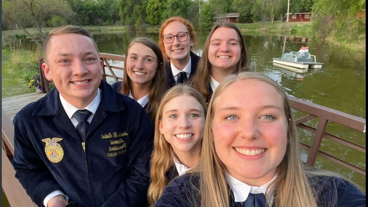 smiling children in navy blue school uniforms standing next to a pond