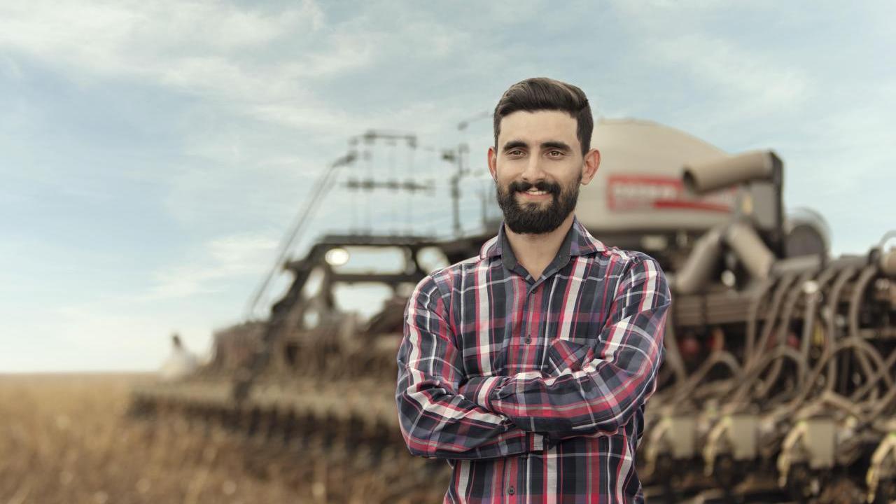 A person standing in front of a tractor in a field