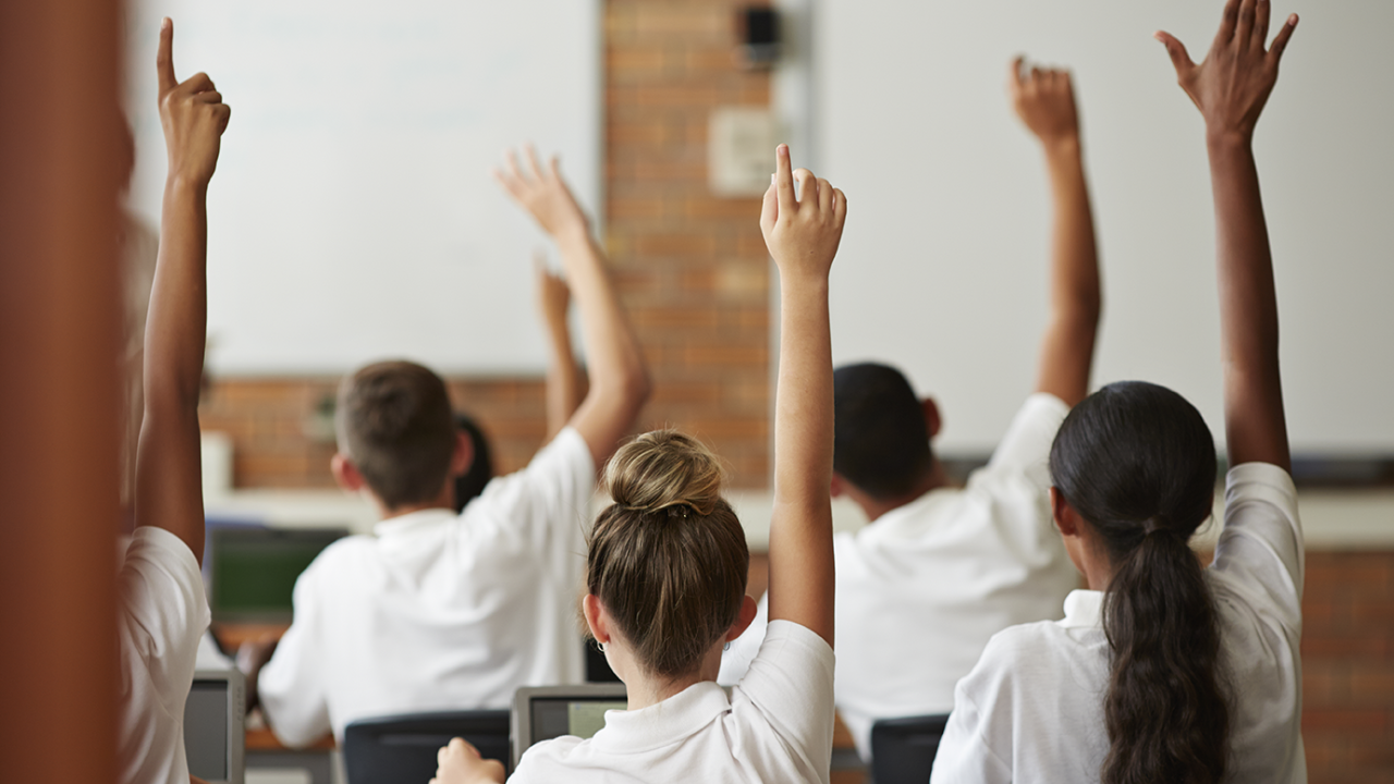 students raising their hands in a classroom