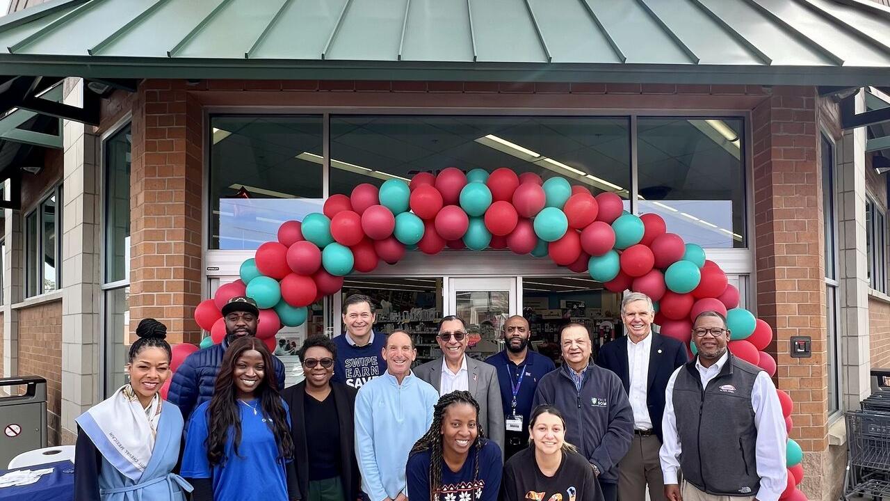 A group of people posed outside a Walgreens. A balloon arch over the entrance.