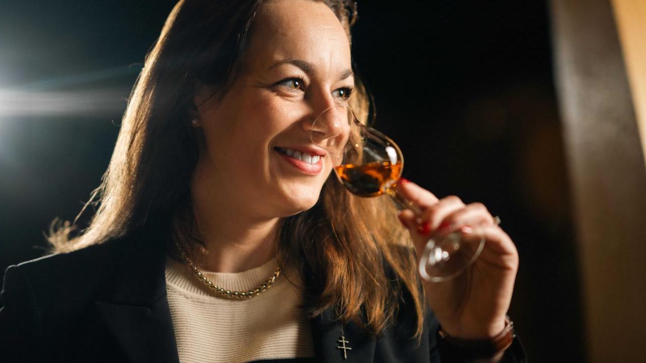 Agathe Boinot smiling, smelling a small glass of cognac.