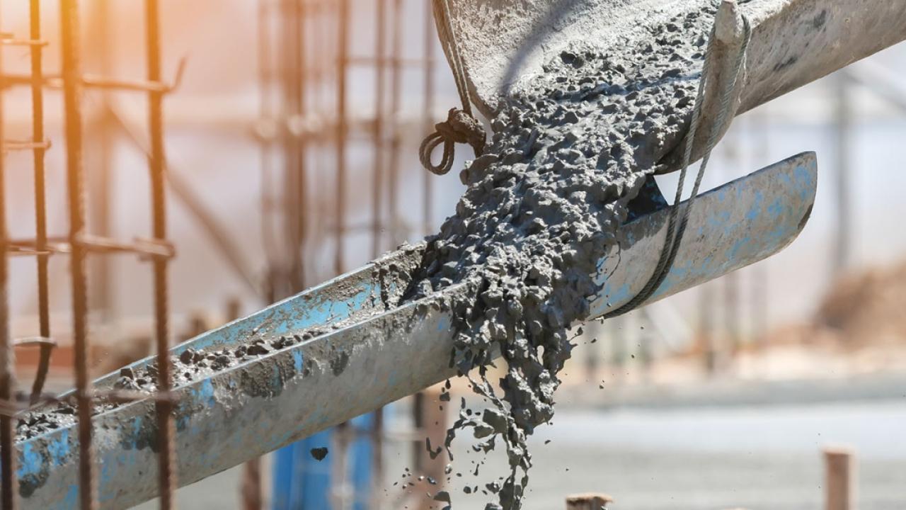 Concrete flowing down troughs at a construction site.
