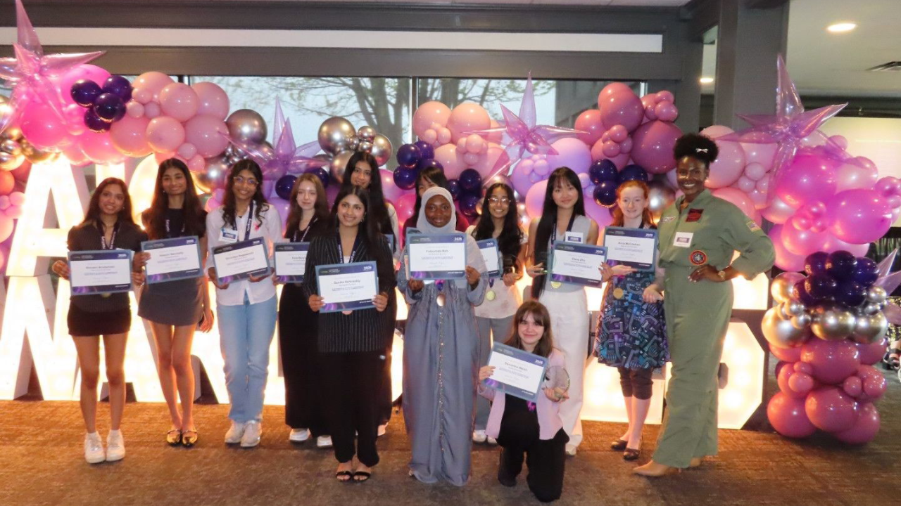 A group holding awards in front of balloons