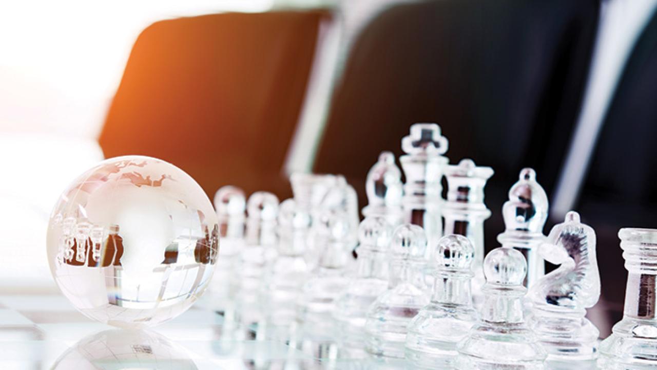 Clear chess set and a small clear globe on a table.