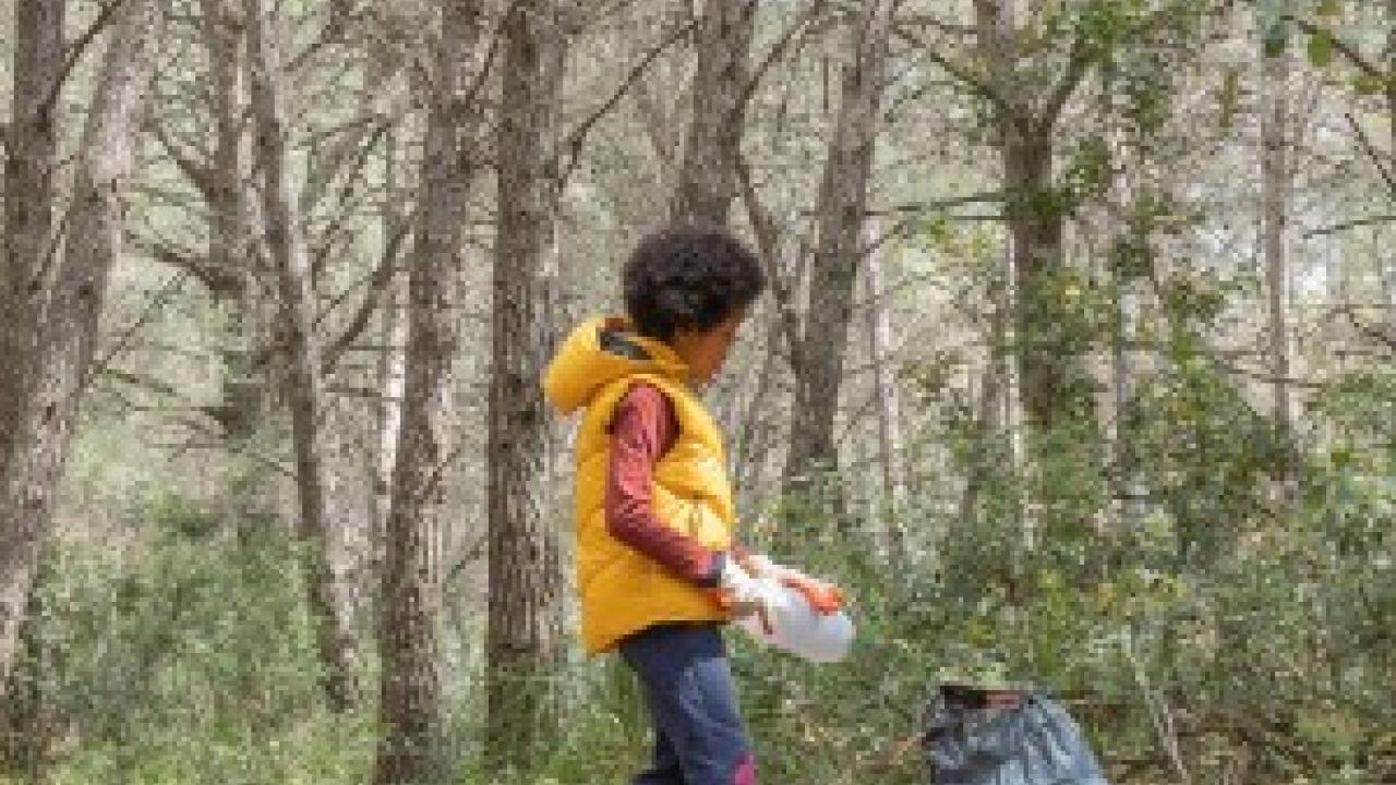 Child picking up a plastic bottle