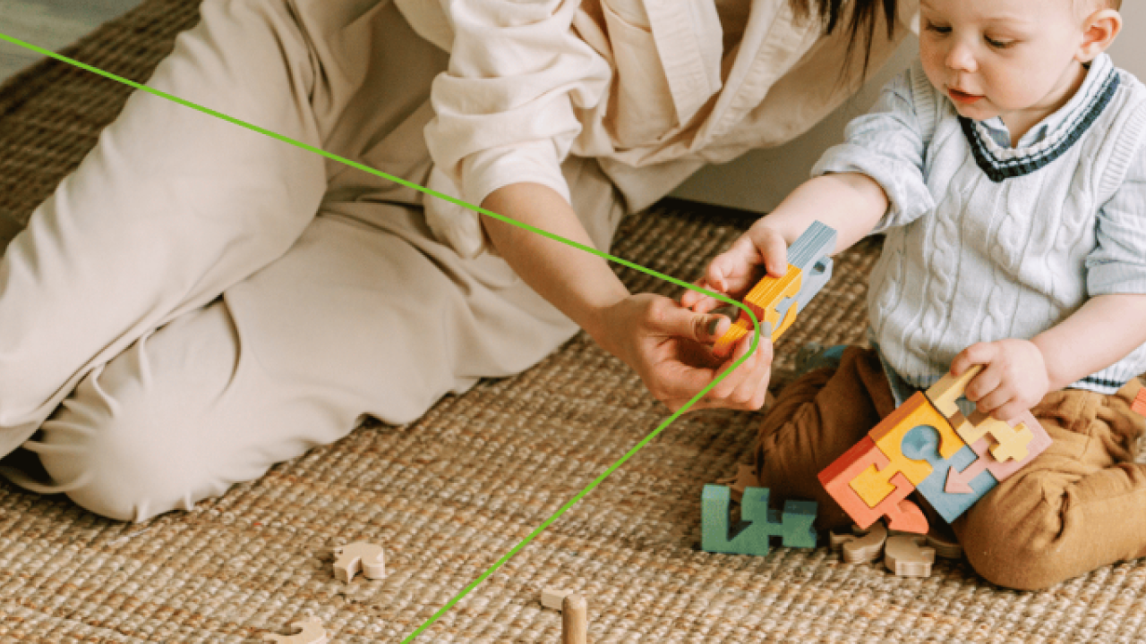 An adult and young child playing on the floor with colorful blocks.