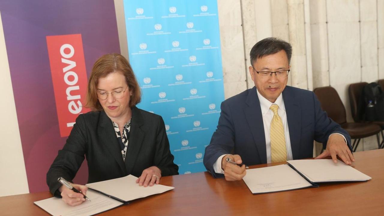 Two people seated at desk, signing letters