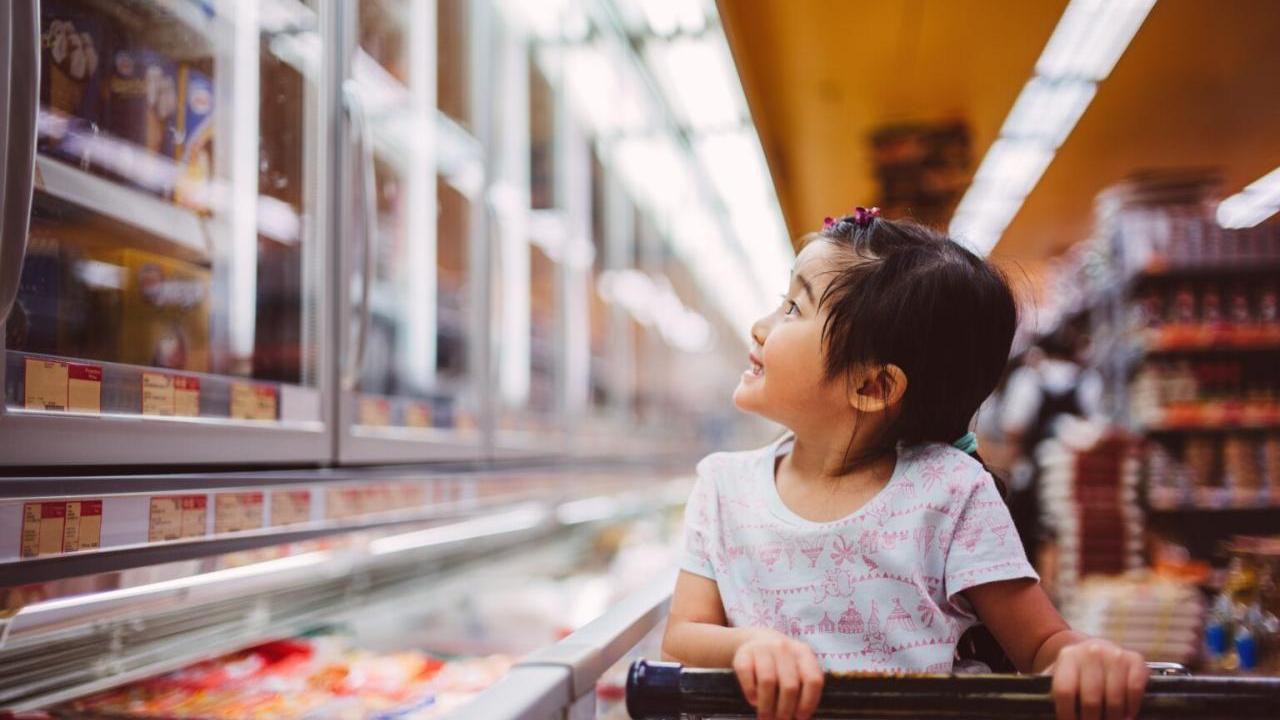 A child seated in a shopping at looking at items