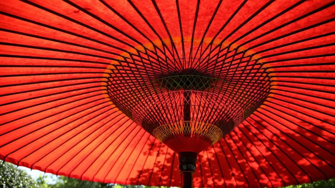 An open, red, fabric umbrella outside.