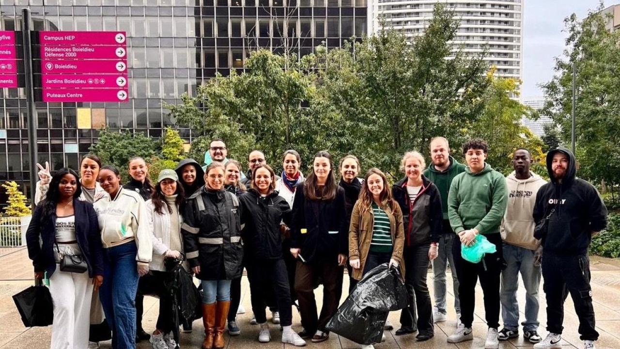 S group posed together outside. Some holding black trash bags.