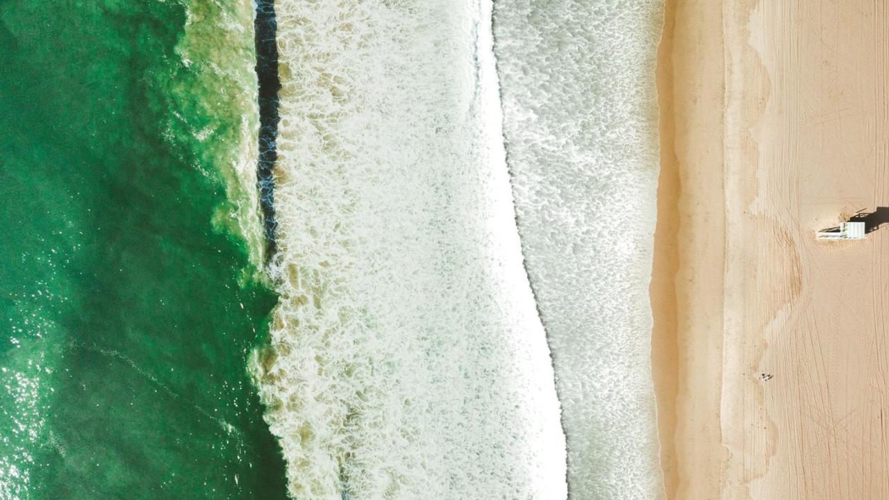 Aerial view of a beach with small waves from greenish water