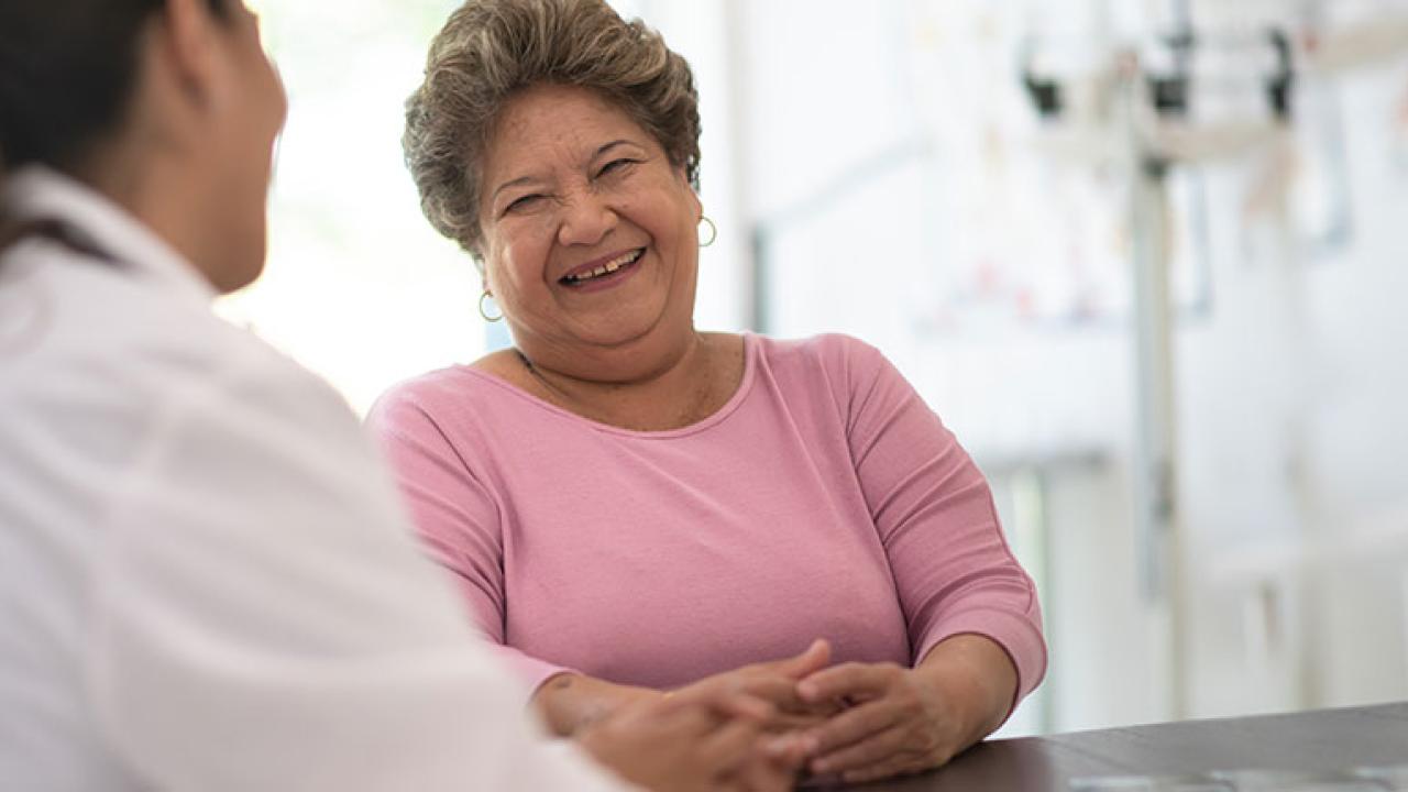 A person smiling at another in a white coat in a medical setting.