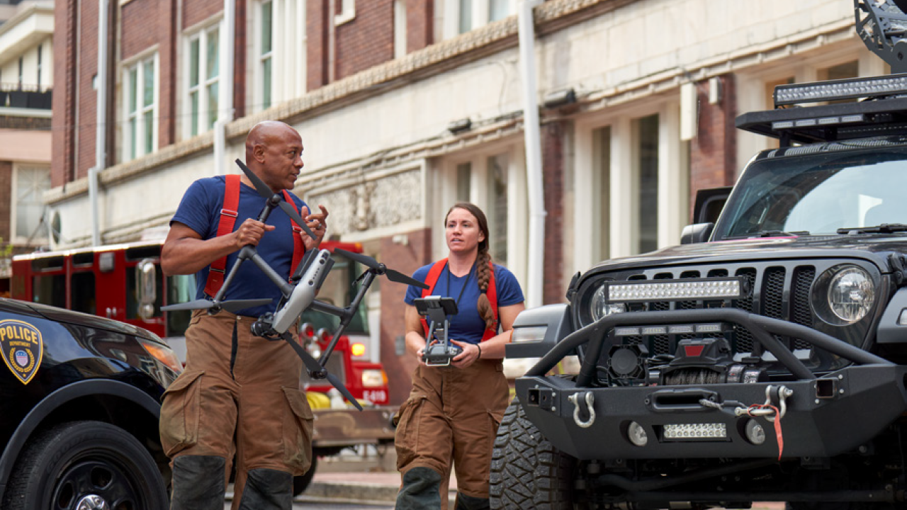 Firefighters carrying a drone near vehicles