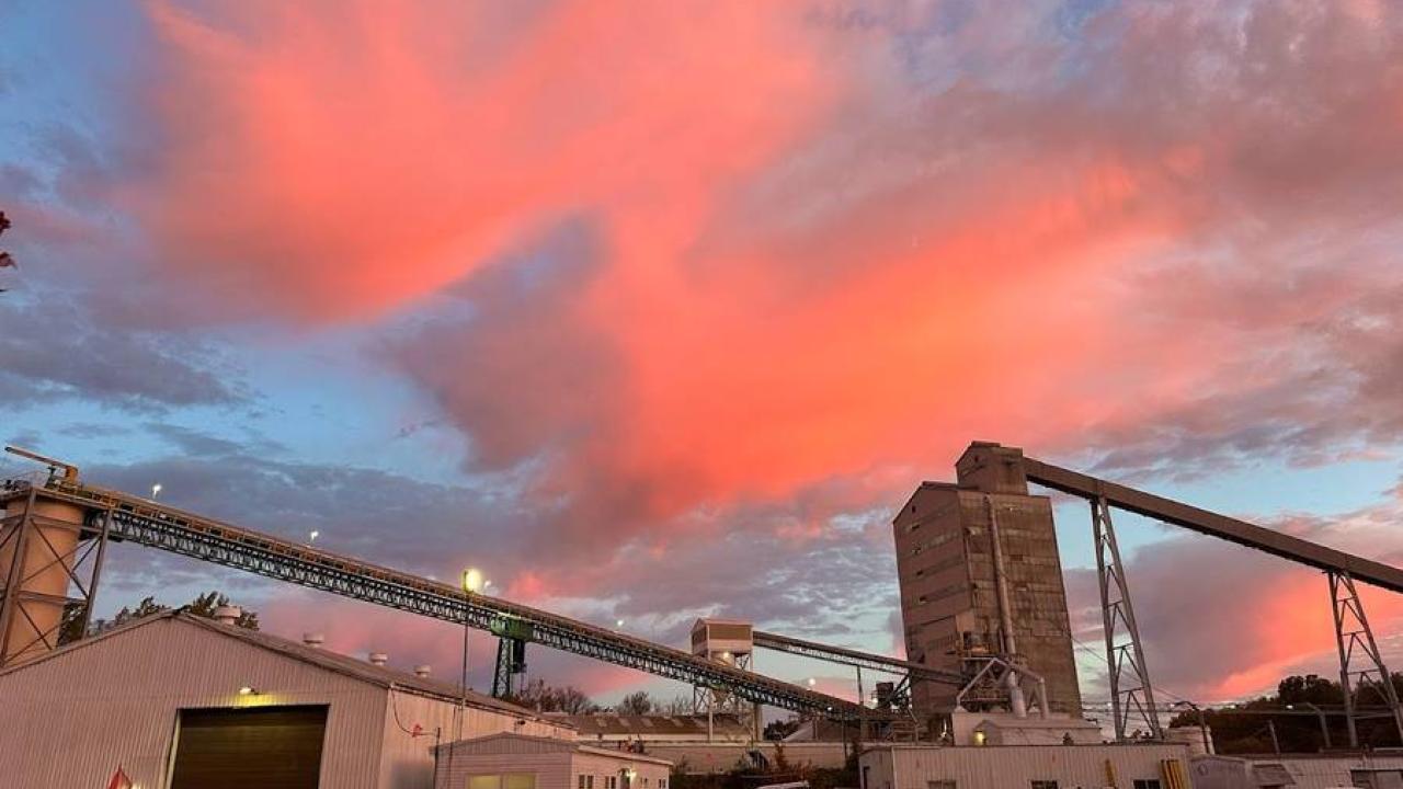 A sunset reflecting on clouds over an industrial setting.