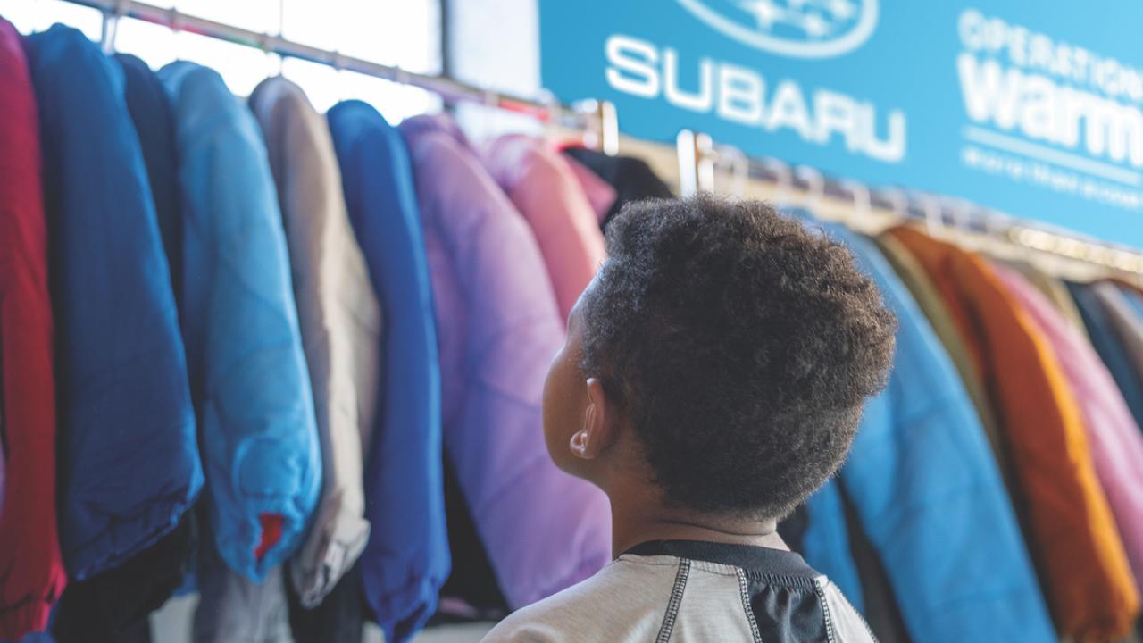 child looks at coats