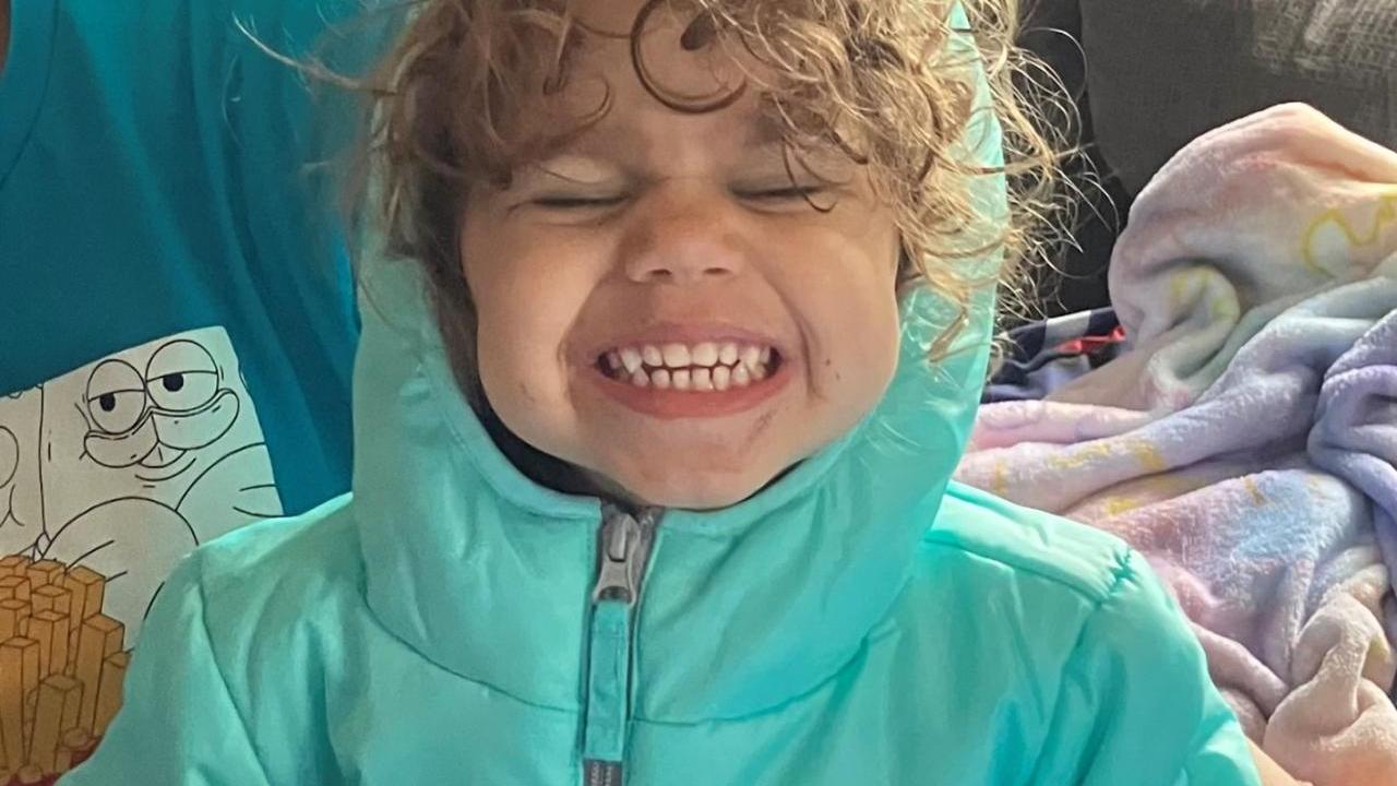 A smiling child in a teal coat