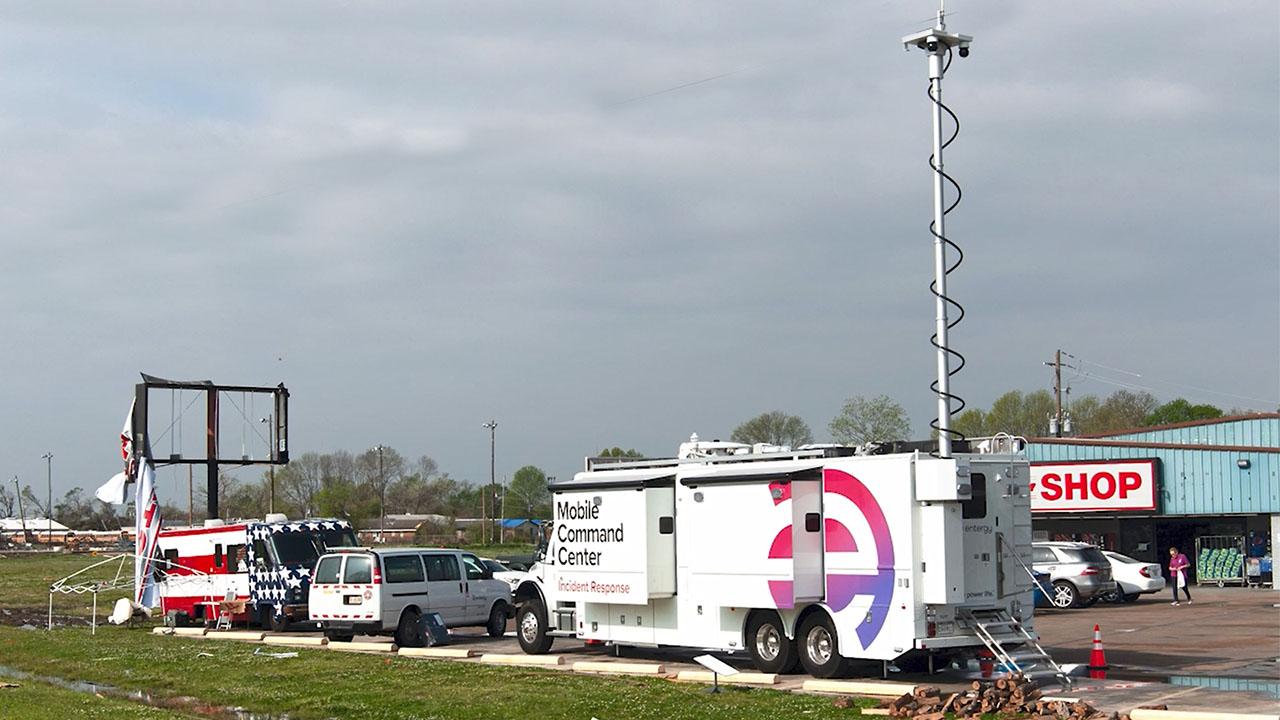 A truck with Entergy logo and Mobile Command Center on the side, antenna raised, parked in a parking lot.