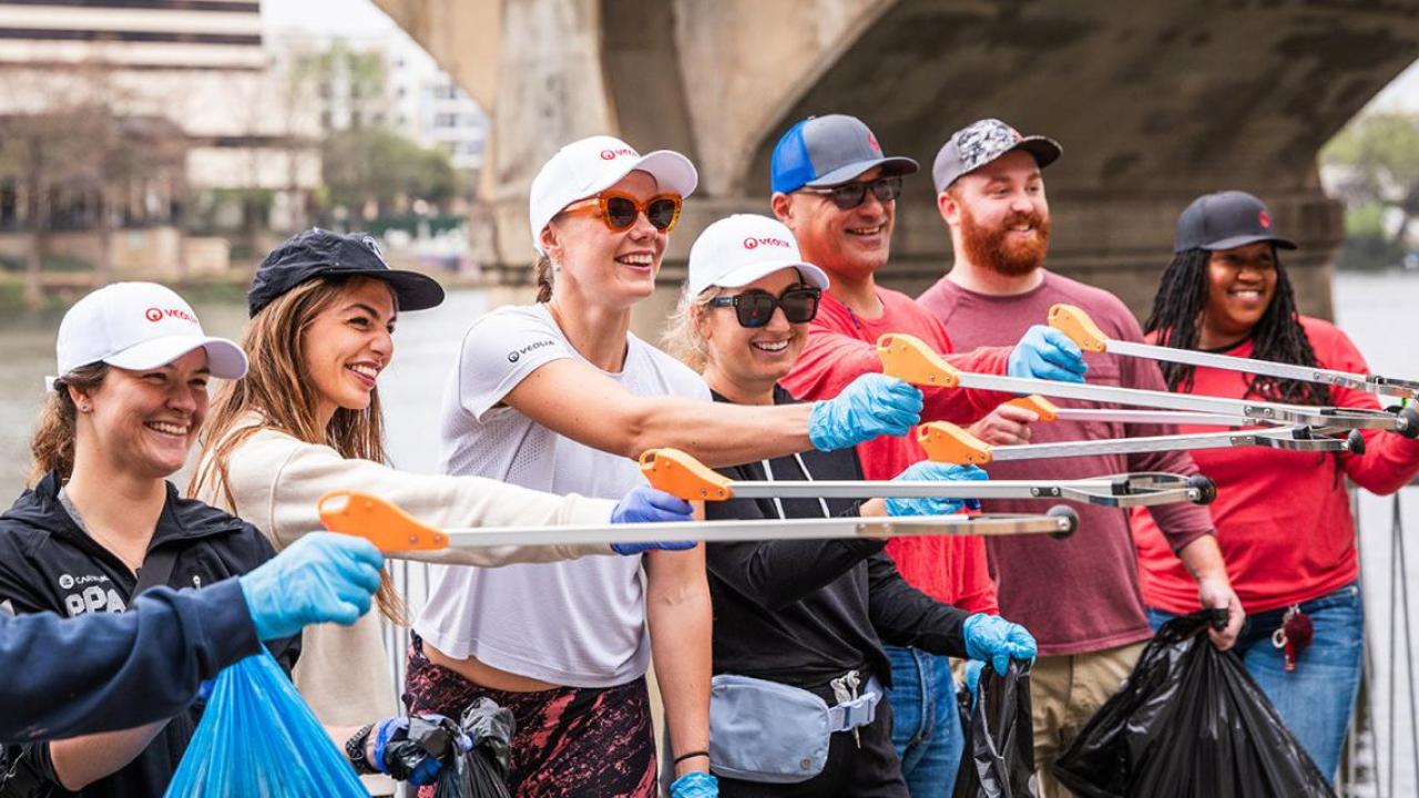 Smiling volunteers posed together extending litter pickers.
