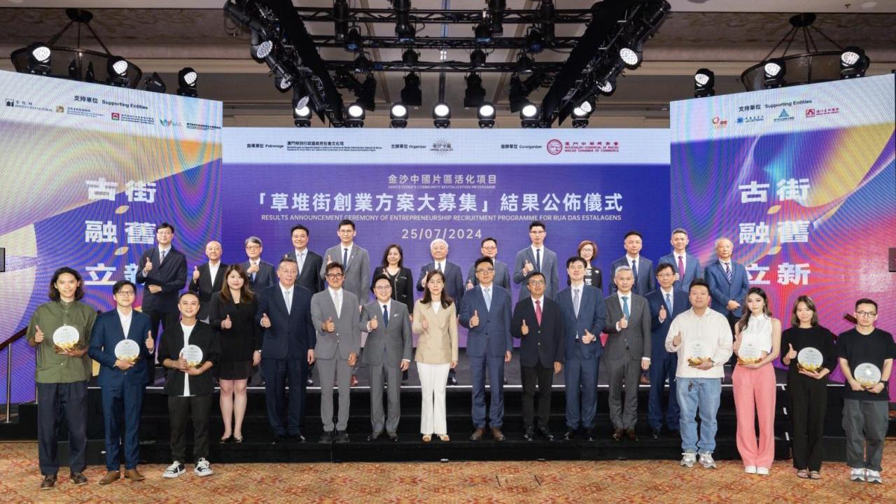 Large group assembled on stage. Some members are holding awards.