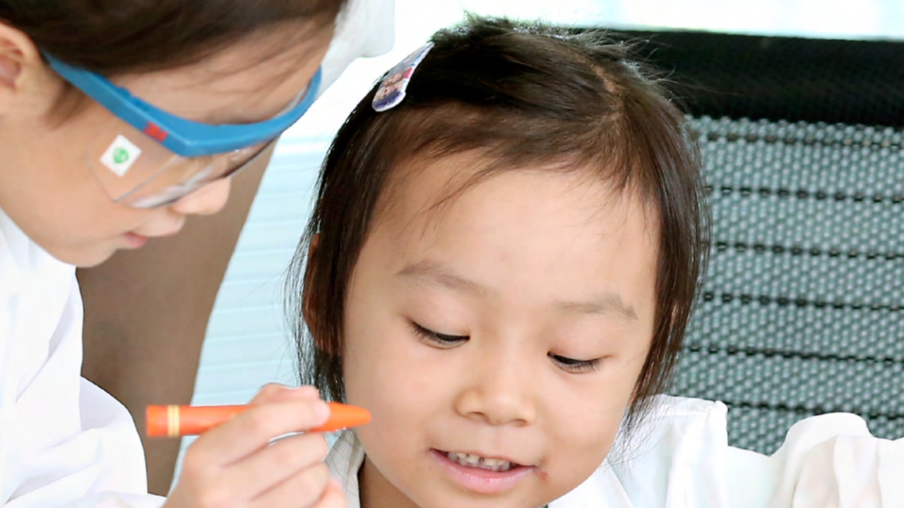 adult looking at a paper with a child holding a crayon