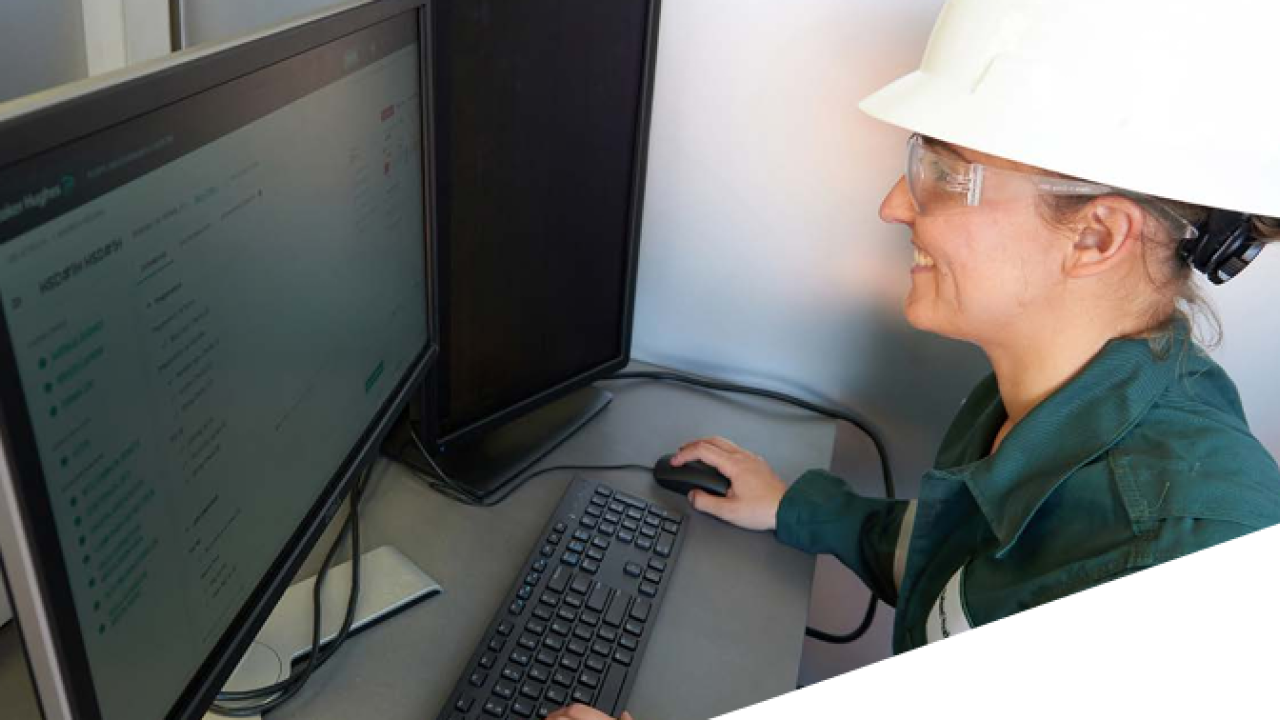 A person in protective gear working on a desktop computer.