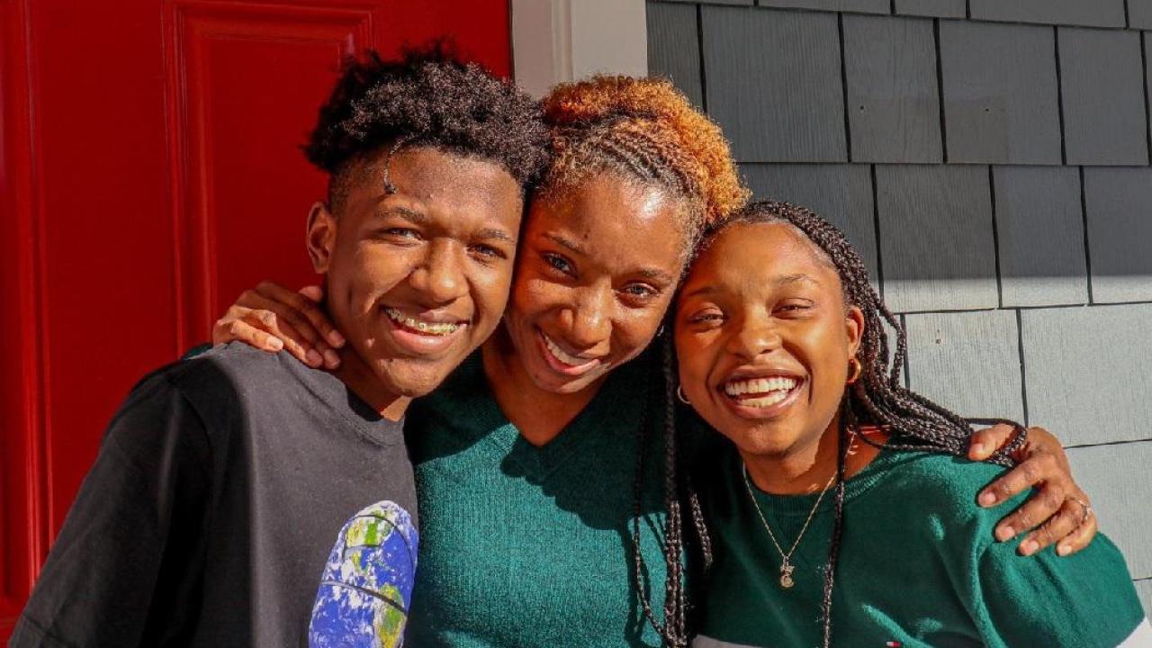 mom standing in center of two teen children