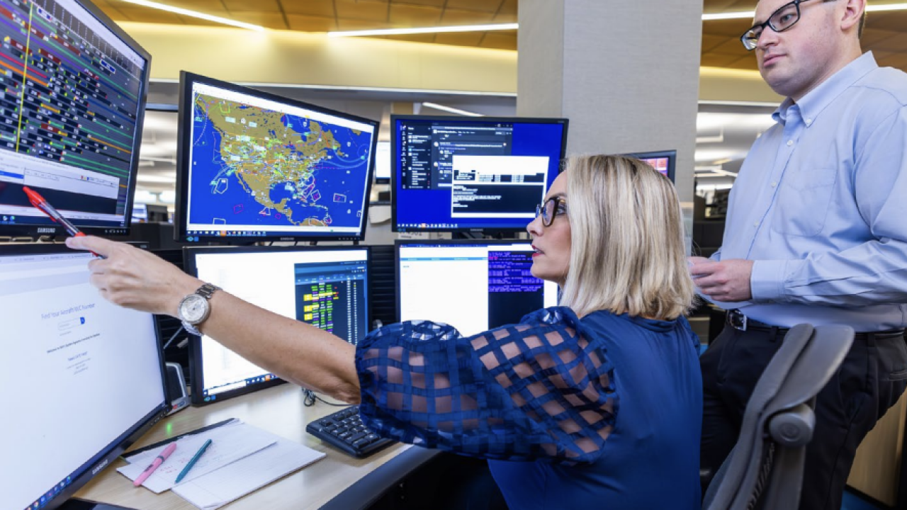 Two people looking at multiple computer monitors 
