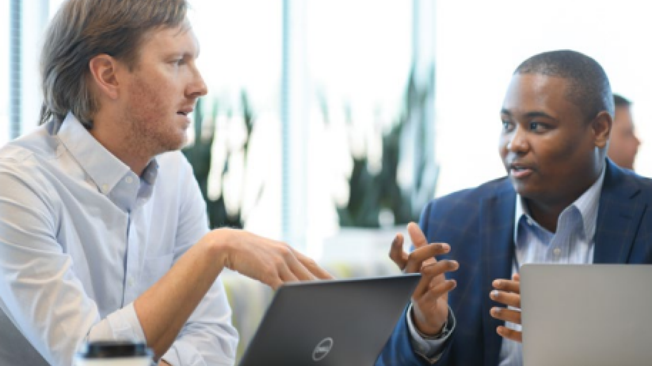 Two people talking while on laptops